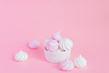 Obraz na płótnie Canvas white and pink twisted meringues in porcelain bowl on pink background, greeting card, copy space
