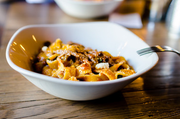Pasta bolognese with cheese in a white plate on the restaurant table. Delicious lunch of pasta.