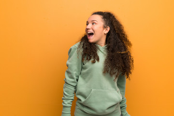Teenager girl over ocher wall smiling