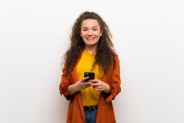 Teenager girl with coat sending a message with the mobile