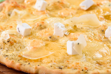 four cheese pizza on a round wooden board on a red wooden background, decorated with napkins, chili pepper and cherry tomatoes. close-up. top view. flat lay