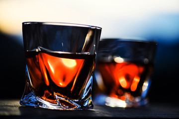 shot of whiskey at sunset dramatic sky on mountain landscape background