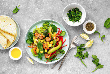 Shrimps and avocado fajita salad with diced mango and greens