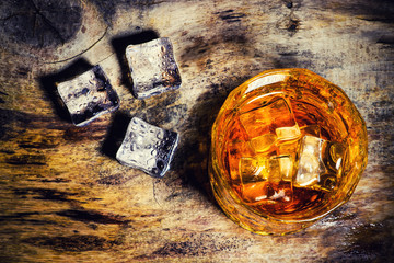 whiskey with ice cubes on wooden background