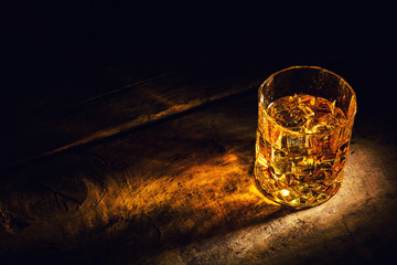 whiskey with ice cubes on wooden background