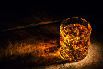 whiskey with ice cubes on wooden background