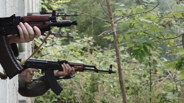 Soldiers aim target out of window at day