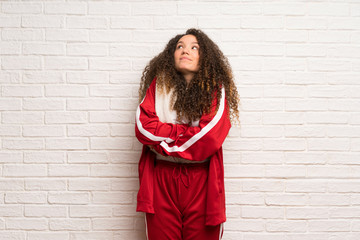 Teenager sport girl with curly hair making doubts gesture while lifting the shoulders