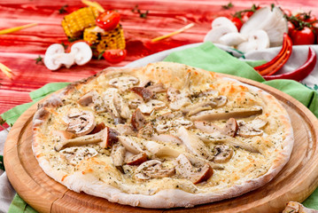 Italian Vegetarian Mushroom Pizza with  cheddar on a round wooden board on a red wooden background, decorated with napkins, chili pepper and cherry tomatoes. close up