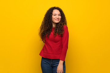 Teenager girl with red sweater over yellow wall