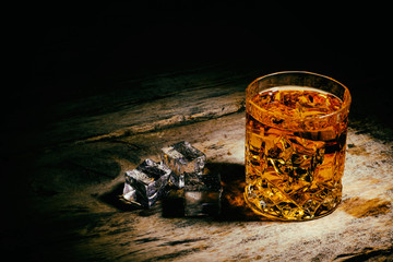 whiskey with ice cubes on wooden background
