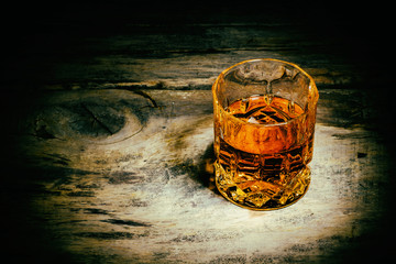 whiskey with ice cubes on wooden background