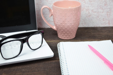 Computer image coffee cup resting on a wooden backgroud. desktop, work space of a journalist, blogger, freelancer, office supplies glasses pen, notebook