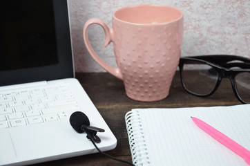 Computer image coffee cup resting on a wooden backgroud. desktop, work space of a journalist, blogger, freelancer, office supplies glasses pen, notebook