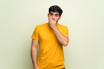 Young man over pink wall covering mouth with hands for saying something inappropriate