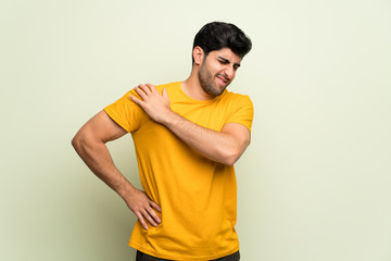 Young man over pink wall suffering from pain in shoulder for having made an effort
