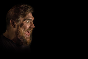Close-up face profile expression portrait strong serious brutal bearded man on black. Confident and dramatic concept