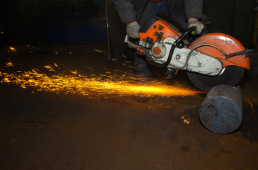 Closeup Worker saws metal with a large circular saw in the hands of the factory workshop, sparks