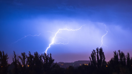 Night lightning storm over city in blue dramatic lighting