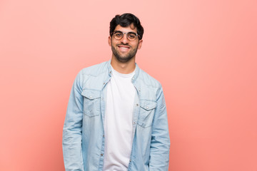 Young man over pink wall with glasses and happy