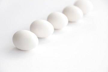 white chicken eggs lined up horizontally on a white background