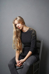 Fototapeta na wymiar teenage girl slouching on chair - gray background with copy space
