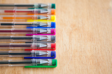Fototapeta premium Multicolored gel pens on the wood ground