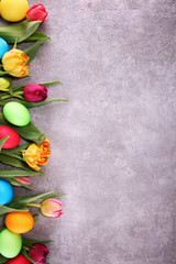 Colorful Easter eggs and tulips on rustic table