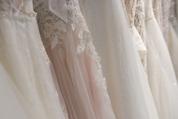 Wedding dresses hang on hangers. Factory of wedding dresses.