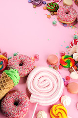 candies with jelly and sugar. colorful array of different childs sweets and treats on pink