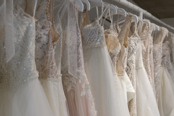 Wedding dresses hang on hangers. Factory of wedding dresses.
