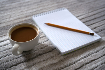 Filiżanka kawy i notatnik z ołówkiem