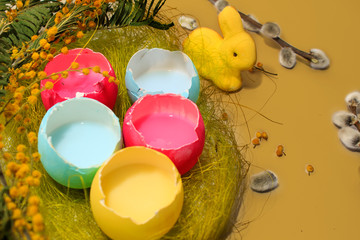 Fototapeta na wymiar Pastel colored easter eggs and bunny in a egg box with a mimosa on yellow background