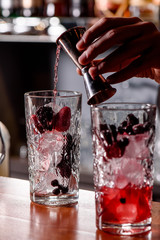 Barman makes two cocktails with berries at the bar close-up. two glasses with berries and ice. The process of making alcoholic beverage. Close up. Space