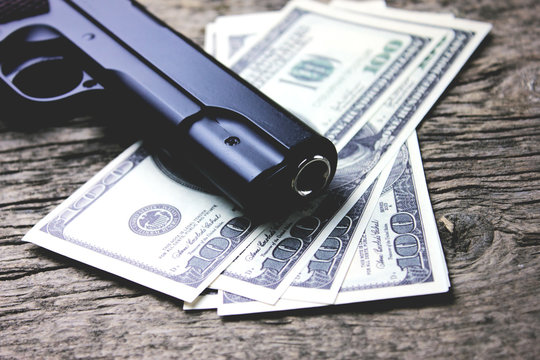 a gun with money on a wooden table