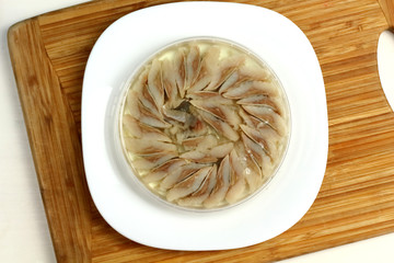 canned russian fish pieces of herring in oil in a jar on a white plate and wooden board  with bread