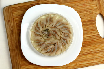 canned russian fish pieces of herring in oil in a jar on a white plate and wooden board 