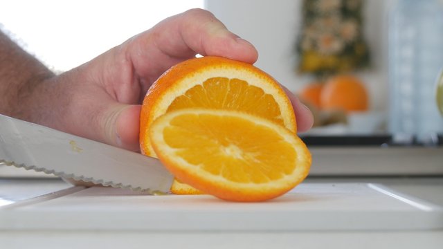 Image with Man Hands in Kitchen Cutting in Slices a Fresh and Sweet Orange Fruit