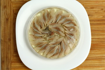 canned russian fish pieces of herring in oil in a jar on a white plate and wooden board 