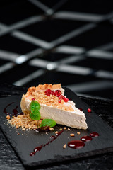 Beautiful serve of cheesecake, decorated with cranberries, mint, pine nuts and red syrup, on a...