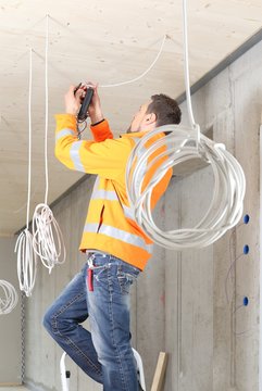 Elektriker arbeitet und installiert in einem Neubau