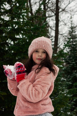 Girl child in pink coat at winter forest