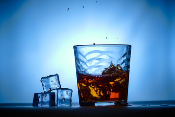 Ice cubes next to a glass of whiskey