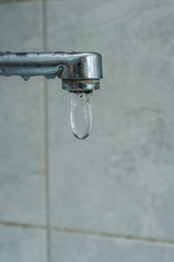 A bunch of water hanging from a tap in the bathroom