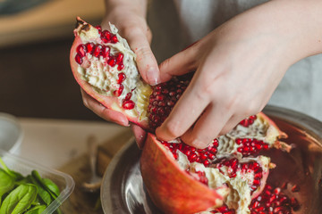 Amateur cuisine - close up female hands take out the grain from the pomegranate