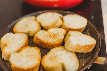 Closeup of housewife frying baguette pieces in a frying pan - making cold snacks - tapas and sandwiches