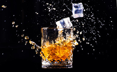 whiskey with splash on black background, brandy in a glass