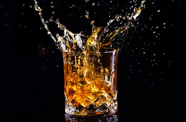 whiskey with splash on black background, brandy in a glass