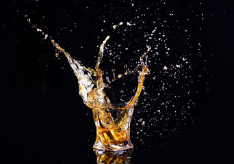 whiskey with splash on black background, brandy in a glass