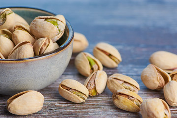 close up color picture of pistachios roasted and salted in a ceramic bowl on a wooden surface
